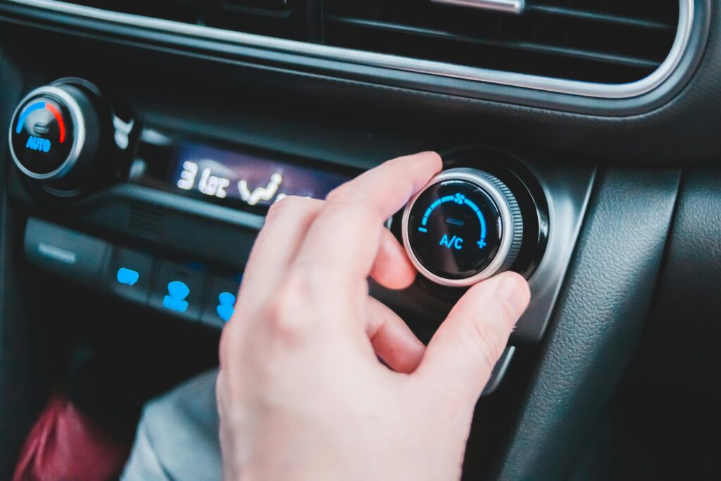 Crop anonymous person regulating temperature in car using controller on panel while sitting in car